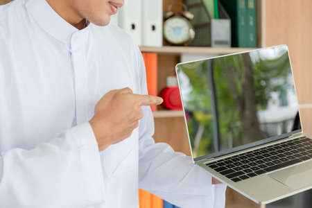 Young business arab middle eastern muslim man showing laptop screen in officeの写真素材