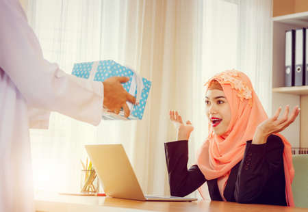 Arabic business muslim man gifting present to girlfriend at office, Romantic surprise concept.