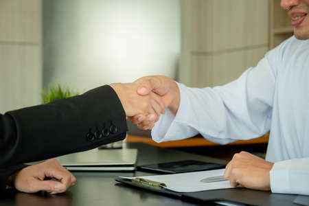 Arab middle eastern businessman and business woman make handshakes, finishing up meetingの写真素材