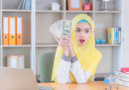 Young business muslim woman holding and showing money banknotes, Arab finance concept.の写真素材