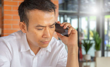 Selective focus of Casual young business man using mobile smart phone with blurred background at coffee shopの写真素材