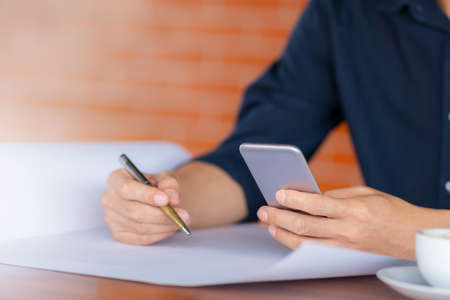 Selective focus of Casual young business man hand using mobile smart phone with silver pen and...
