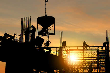 Silhouette of Engineer and worker checking project at building site background, construction site at...