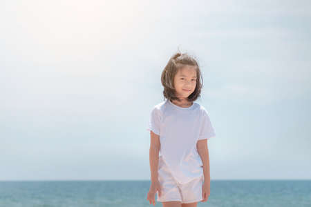 Smile little girl standing enjoy on the beach and looking to camera blurred backgroundの写真素材