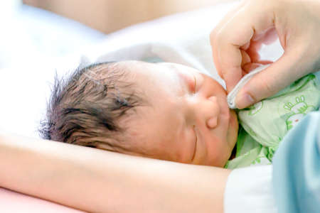 Selective focus of Happy asian mother looking newborn baby boy sleeping in hand at hospitalの写真素材