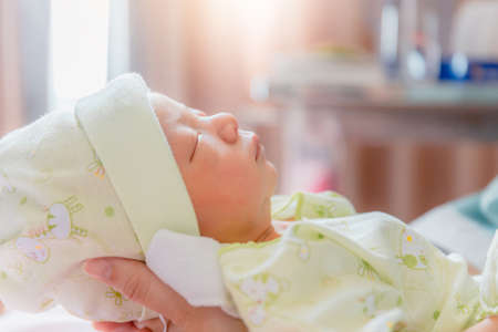 Newborn baby boy sleeping in asian mother hand at hospital