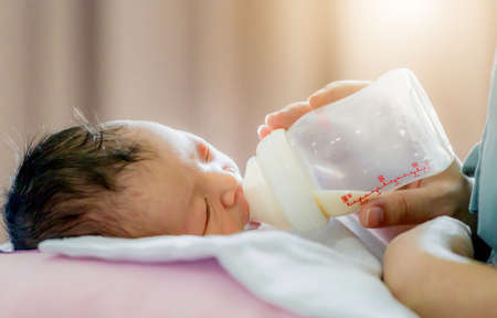 Mother holding and feeding newborn baby from milk bottle, Love conceptの写真素材