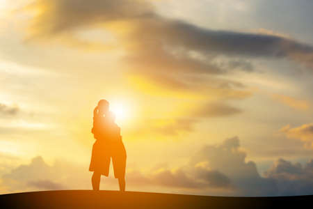 Silhouettes of mother and son playing at sunset evening sky background.の写真素材