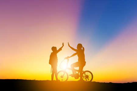 Silhouettes of mother and son playing at sunset evening sky background.の写真素材