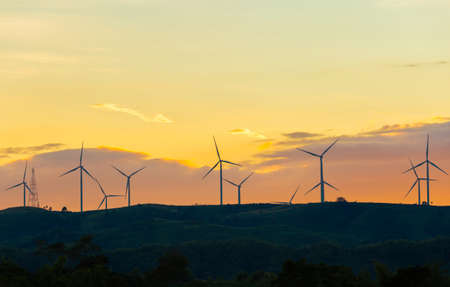 Silhouette of wind turbines at sunset in evening time, alternative energy concept.