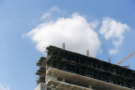 Building under construction against white cloudy the blue clear sky and big crane at the top with copy space.の写真素材