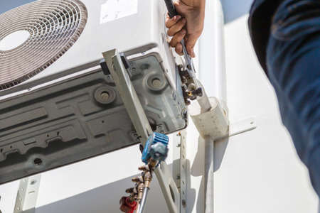Selective focus of technician man hands using a wrench fixing modern air conditioning systemの写真素材