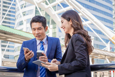Young businesswomen and smart business man with smartphone and coffee cup in handの写真素材