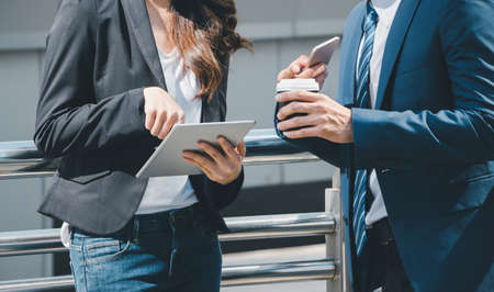 Close up of young businesswomen and smart business man with smartphone and coffee cup in handの写真素材
