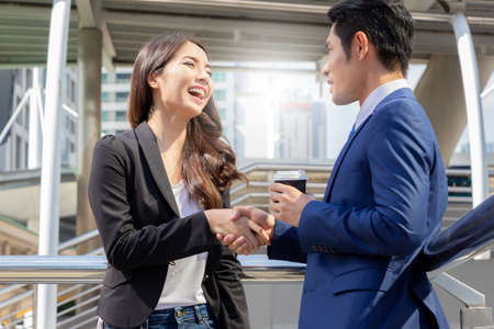 Close up of happy young businesswomen and smart business man with smartphone and coffee cup in handの写真素材