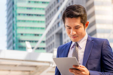 Close up of Business man with tablet over blurred city backgroundの写真素材