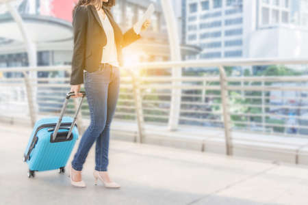 Businesswoman traveler with luggage and looking smartphone in city blurred background, with clipping path.の写真素材