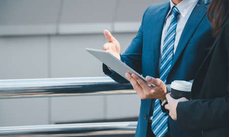 Close up of young businesswomen and smart business man with smartphone and coffee cup in handの写真素材