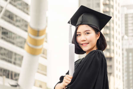 Close up of graduate student holding a diploma and looking at camera, Education concept.の写真素材