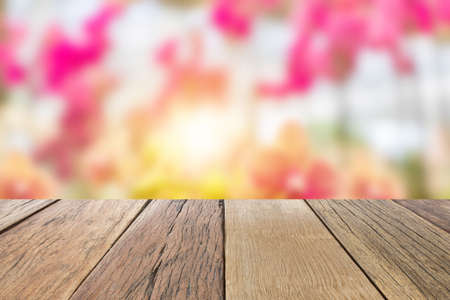 Empty wooden table top perspective with blur beautiful orchid flower natural background, used for...