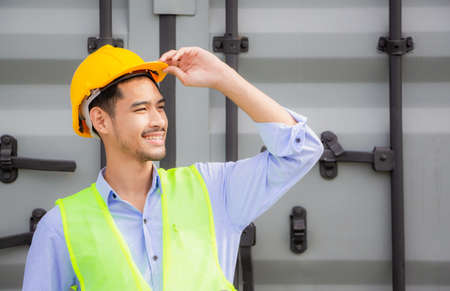 Cheerful factory worker man in hard hat looking the sky with joy, Happiness engineer at cargo...