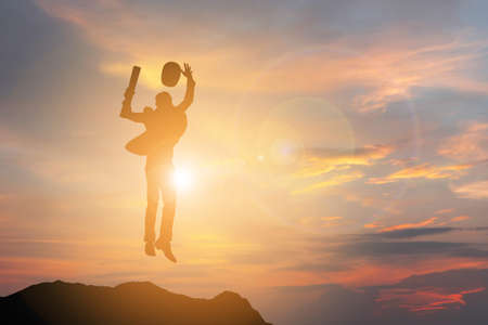 Silhouette of Business engineer man Celebration Success Happiness on a mountain top Sunset Evening Sky Background, Sport and active life Concept.の写真素材