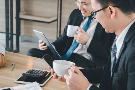 Group of Business Team Meeting Strategy Marketing in a coffee shop chatting to each other while using smartphone tablet laptop internet of thingsの写真素材