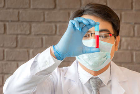 Doctor analyzing medical test tubes examining beaker with red fluid, Scientist researching and learning in a laboratoryの写真素材