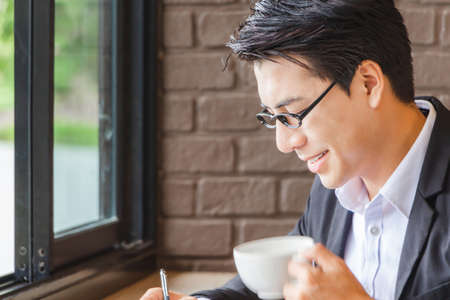 Happiness young businessman holding mug of coffee while working, Work from home conceptの写真素材