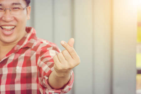 Close up of a man show finger heart symbol with copy space, message of love hand sign concept.