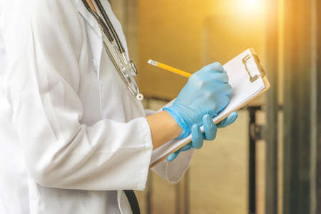 Close up of portrait a female doctor holding her medical chart document or patient examination notesの写真素材