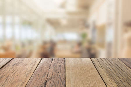 Empty wooden table top perspective with blur coffee shop background, used for montage or display your products.の写真素材