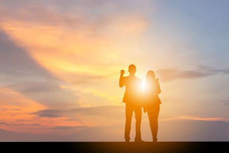 Silhouette of Business Man and Businesswoman Celebration Success Happiness People Team at Sunset Evening Sky Background.の写真素材