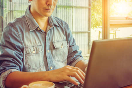 Engineering business man in blue jean using a notebook for work in coffee shopの写真素材