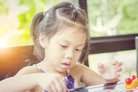 Portrait of little girl playing toy in coffee shop.の写真素材