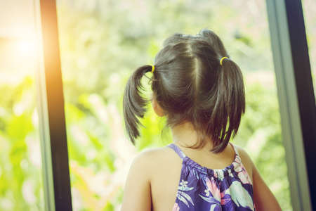Little girl looking at the green gardenの写真素材