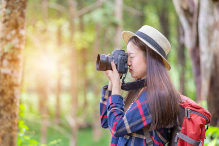 Young traveler woman with backpack and hat standing with camera travel photo of photographer making pictures in hipster styleの写真素材