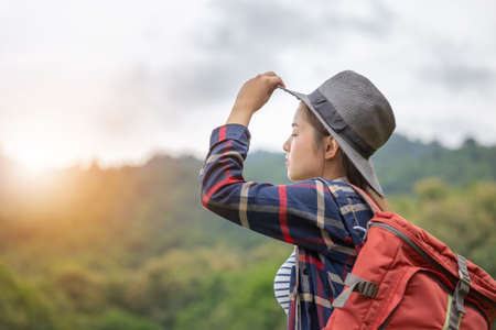 Young traveler woman in hipster style with backpack and hat standing looking the skyの写真素材