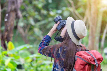 Young traveler woman with backpack and hat standing with camera travel photo of photographer making pictures in hipster styleの写真素材
