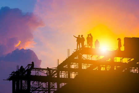 Silhouette of Engineer and worker on building site, construction site with clipping path at sunset in evening time.の写真素材