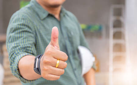 Business engineer man giving thumb up as sign of Success over blurred construction site backgroundの写真素材