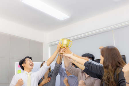 Business team holding award trophy show their victory when business success at meeting room