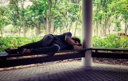 Homeless man sitting on the floor in the cities park.の写真素材