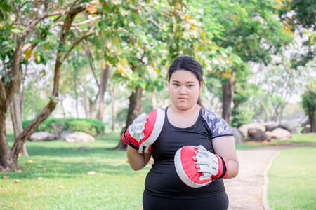 Young plus size model girl with boxing gloves in the park