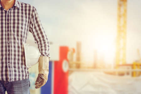 Engineer, foreman holding white helmet over blurred construction site background, Construction Concept.の写真素材