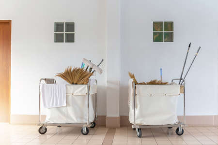 Cleaners trolley with cleaning equipments at hotel with wall background