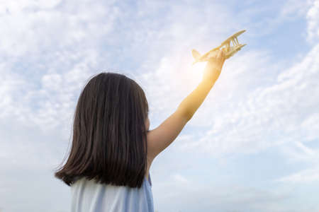 Little girl kid playing airplane toy model with sunset backgroundの写真素材