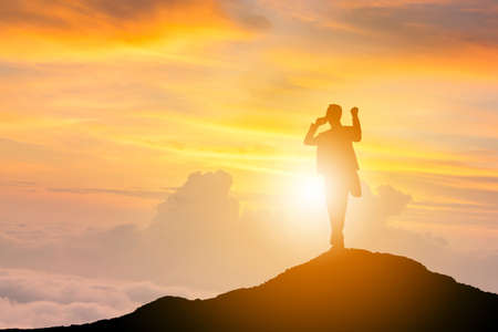 Silhouette of Business man Celebration Success Happiness on a mountain top Sunset Evening Sky Background, Sport and active life Conceptの写真素材