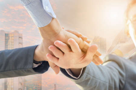 Success Teamwork Concept, Ant's Eye View Business people joining hands city sunset double exposure background.の写真素材