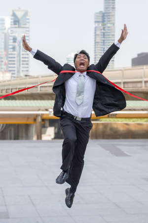 Success and Happiness concept, Cheerful business man crossing the finish line of racing track city background.の写真素材